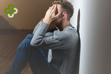 Мужчина сидит и держится за голову